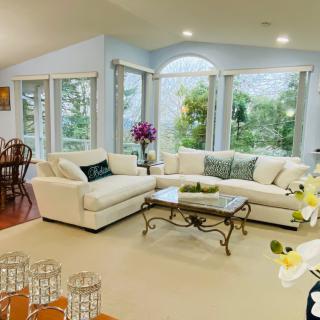 A bright and spacious living room featuring a comfortable sectional sofa, elegant coffee table, and large windows that allow natural light to fill the space.