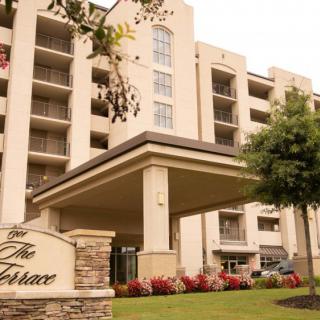A multi-story apartment building with a landscaped entrance and modern architecture.