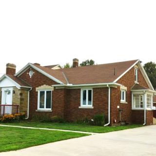 A suburban brick house with a well-maintained lawn.