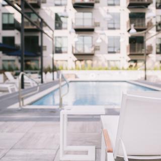 A modern apartment complex with a swimming pool and outdoor seating area.
