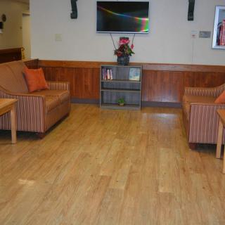 A cozy waiting room with two sofas, a television, and wooden flooring.