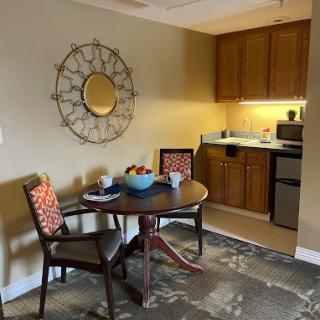 A cozy kitchenette with a dining area featuring a round table, two chairs, and wall decor.