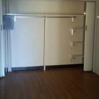 An empty closet space with shelving and a wooden floor.