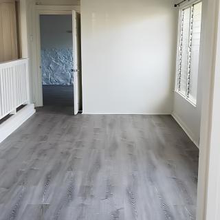 An empty room with gray flooring, white walls, a window, and an open door.