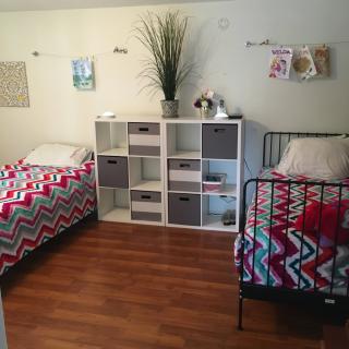 A cozy bedroom with twin beds featuring colorful zigzag pattern bedding and a central storage unit on a wooden floor.