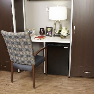A small workspace with a desk, chair, lamp, and decorative items.