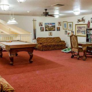 A spacious game room with a billiard table, surrounded by sofas and a small dining setup.