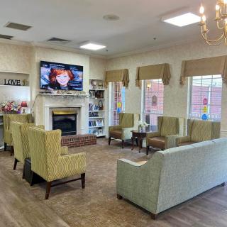 A cozy lounge with comfortable seating and a television above the fireplace.