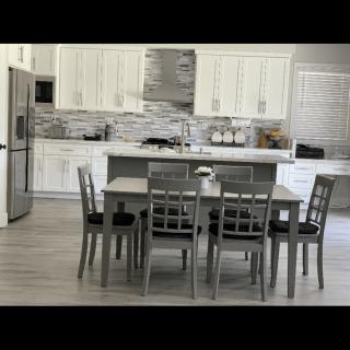 A modern kitchen with a dining table and chairs set, featuring light cabinetry and sleek appliances.