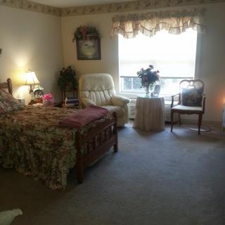 A cozy bedroom with a bed, armchair, and window with natural light.