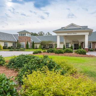 A well-maintained building with a landscaped front yard under a partly cloudy sky.