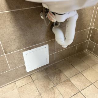 A bathroom sink with visible plumbing and a wall vent beneath it.