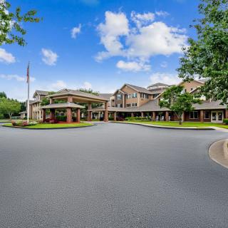 A wide-angle view of a large building complex with a circular driveway under a blue sky.