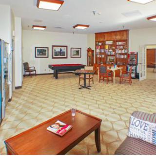 A cozy lounge area featuring comfortable seating, a bookshelf, and recreational amenities.