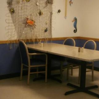 A dining area with nautical decor, featuring a net with seashells and a crab on the wall.