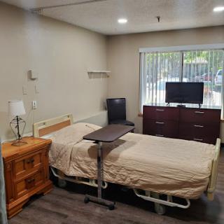 A well-equipped hospital room featuring a patient bed, a television, and a wooden dresser.