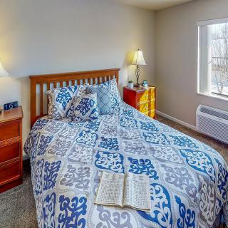A cozy bedroom with patterned bedding and warm lighting.