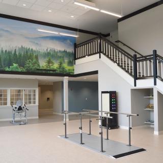 A spacious lobby area with a staircase, mural, and handrails.