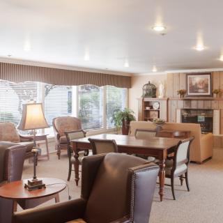 A cozy living room with comfortable seating and a fireplace, illuminated by natural light.