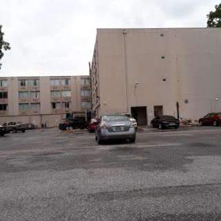 A view of a parking lot with several cars parked near a multi-story building.