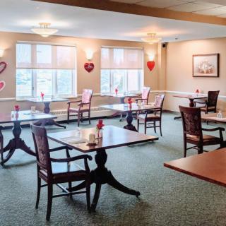 An empty dining room with neatly arranged tables and chairs, decorated with heart ornaments on the walls.