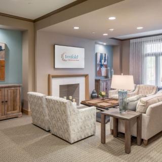 A cozy and elegantly decorated living room with a fireplace, comfortable seating, and tasteful artwork.