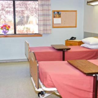 A hospital room with two neatly made beds and a window providing natural light.