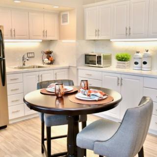 A modern kitchen with white cabinets, featuring a small dining area with a round table and two chairs.