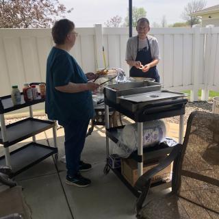 Two people grilling on a patio.