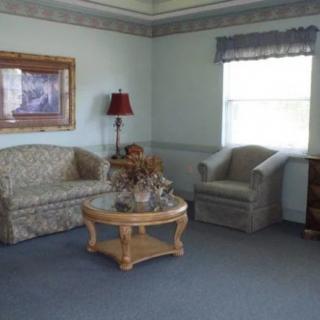 A cozy living room with a couch, armchair, coffee table, and a lamp next to a window.