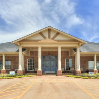 Front view of a building with columns and a porch under a blue sky.