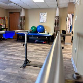 A physical therapy room equipped with parallel bars and exercise balls.