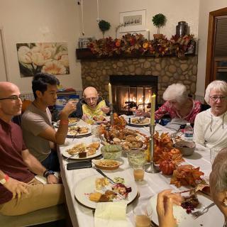 A family enjoying a festive dinner together by the fireplace with autumn decorations.