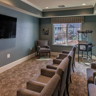 A cozy theater room with several chairs facing a television and a popcorn machine by the window.