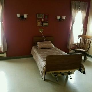 A simple room with a hospital bed and wooden furniture.