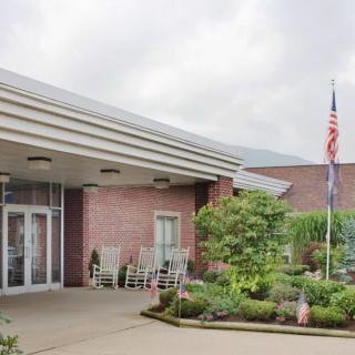An entrance to a building with a small garden and an American flag in the foreground.