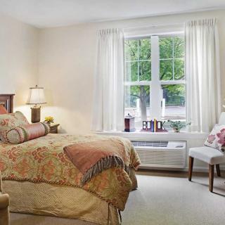 Cozy bedroom with a bed, lamp, and window view.
