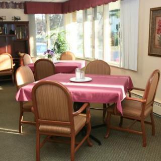 Cozy dining area with tables and chairs, illuminated by sunlight through large windows.