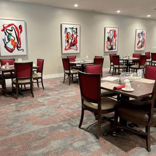 A modern dining area featuring several tables and chairs, decorated with abstract artwork on the walls.
