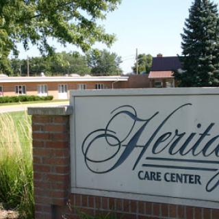The entrance sign of Heritage Care Center, a healthcare facility surrounded by greenery.