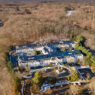 Aerial view of a large luxury mansion surrounded by forests.