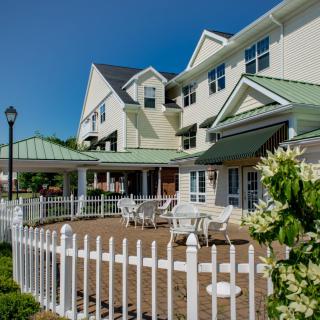 A well-maintained residential building with a fenced patio area featuring outdoor seating.