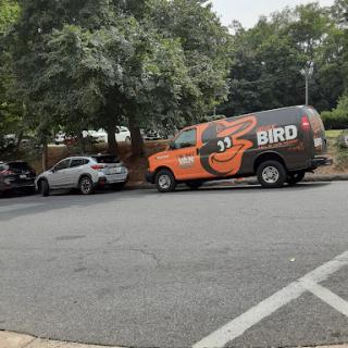 A Bird delivery vehicle parked alongside other cars in an urban setting.