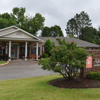 A charming building entrance surrounded by well-maintained landscaping and a sign at the front.