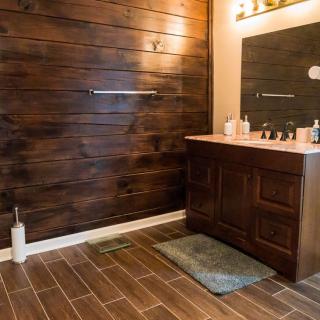 A modern bathroom with wooden walls, featuring a vanity with a mirror and sink.