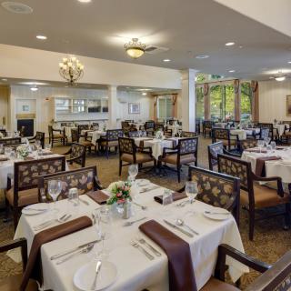 An elegantly set dining room with neatly arranged tables and chairs, ready for guests.