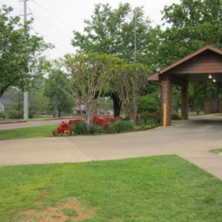 A peaceful park scene with a wooden pavilion and well-maintained landscaping.