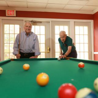 Two men enjoying a game of billiards in a game room.