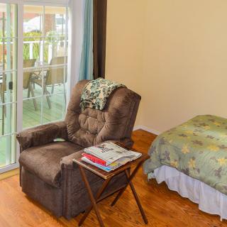 A cozy corner featuring an armchair with a blanket, a side table with magazines, and a view of the patio through sliding glass doors.