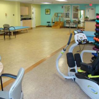A spacious physical therapy and rehabilitation center equipped with various exercise machines and equipment.